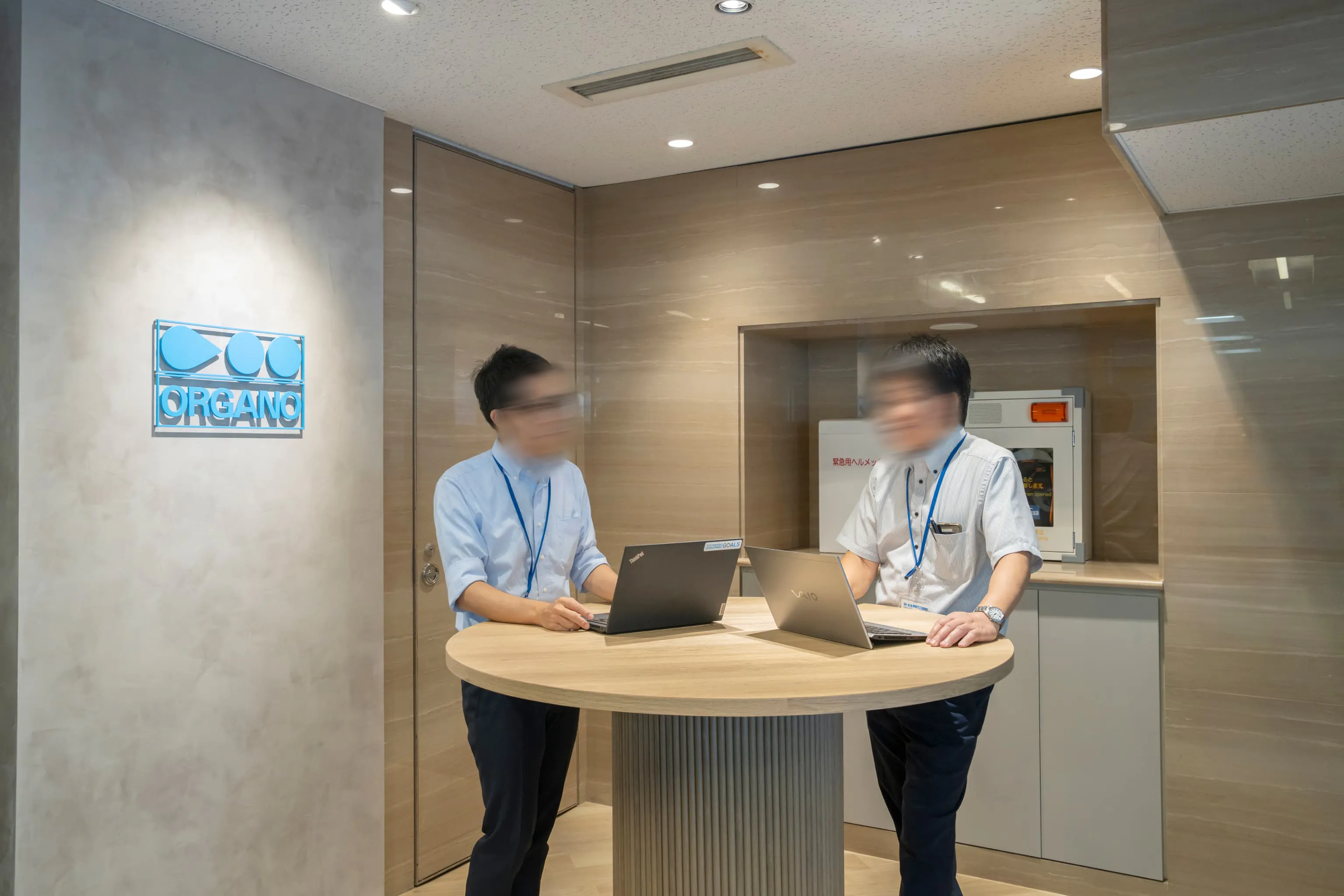 オルガノ株式会社 様の事例写真／[1Fエントランス]1階のエントランスは、使われていなかった受付カウンターを取り払い、丸テーブルが据えられました。来客との待ち合わせや、軽い打ち合わせもできるスペースとして活用されています。