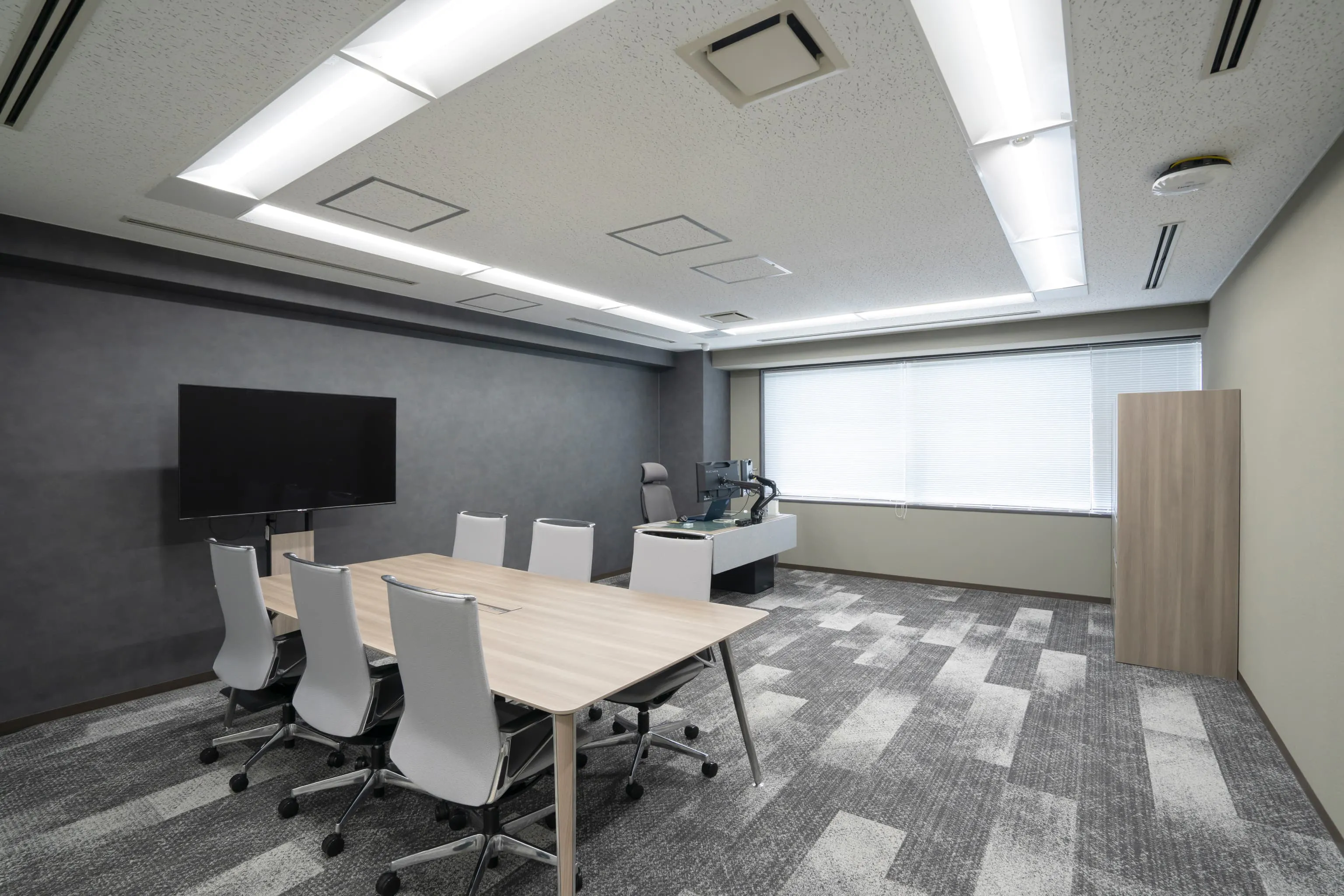オルガノ株式会社 様の事例写真／[9F支店長室]シックなグレーとベージュの壁に市松模様の床を合わせ、奥行きとリズム感を演出。改装前はローテーブルにソファのみでモニターがなく、軽い打ち合わせや相談時も別室に移動していましたが、不便が解消されました。